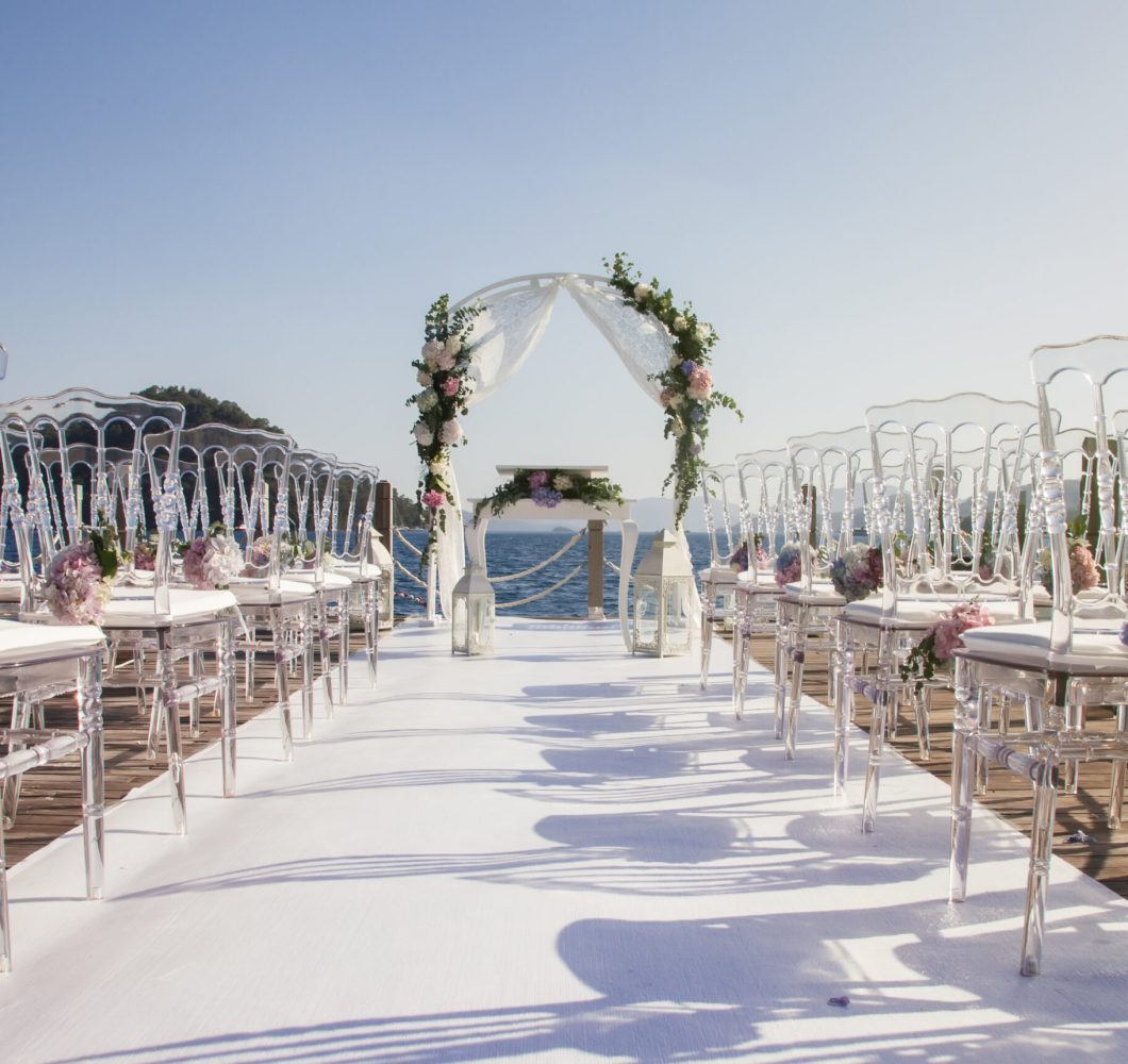Magnificent design of wedding ceremony on coast of azure sea. Arch for newlyweds marriage registration in modern style. Venue of luxury wedding with amazing landscape. Copyright space for site